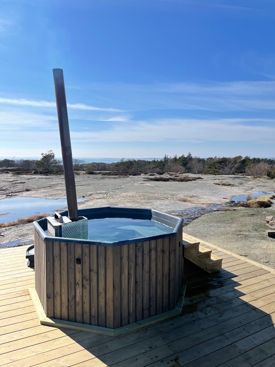 Ångande badtunna på klippor i Bohuslän under kvällsljus